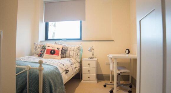 Image of student bedroom with bed and desk visible